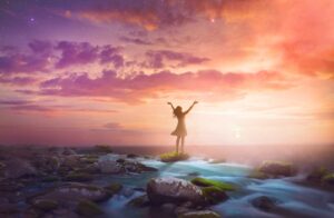 A transformed woman lifts her arms in praise at sunset