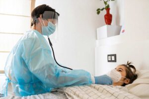 medical doctor in white scrub suit with patient lying on bed